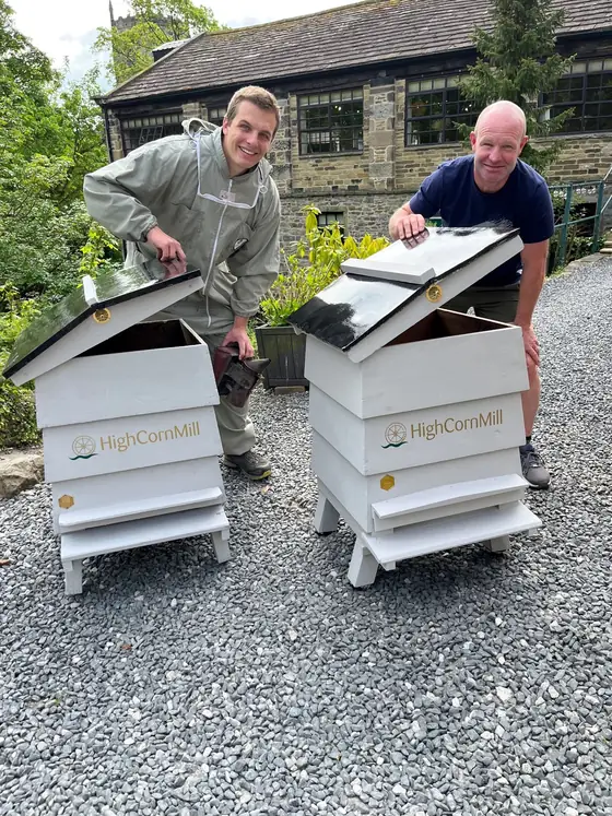 A beekeeper opening the top of a hive