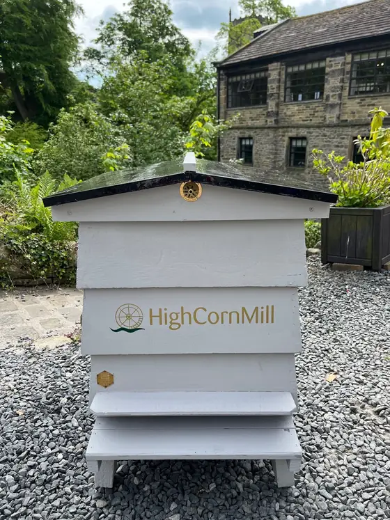 Two white beehives branded High Corn Mill standing on gravel