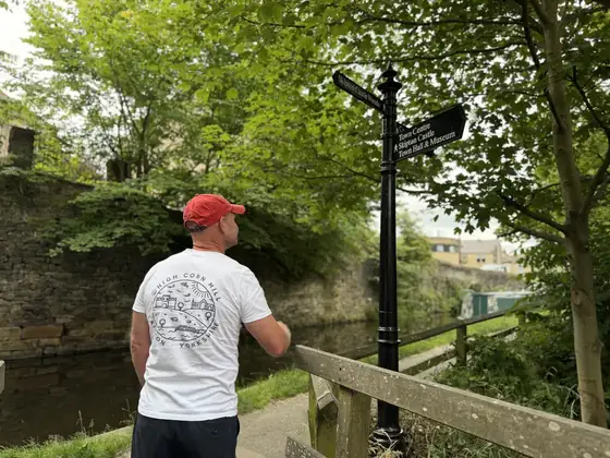 A man looking at the canal-side signpost on the path up to the mill