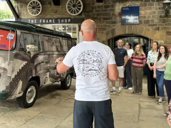A guide talking to a group beside the camper van in the courtyard