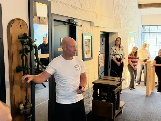 A guide standing beside a large piece of mill machinery