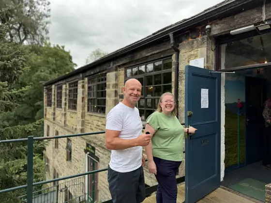 Two people standing in the open doorway of the mill
