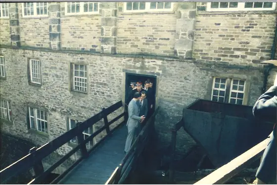 The Prince of Wales walking onto the timber footbridge over the beck