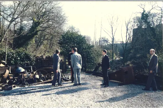 The party walking through the gravel yard beside the mill