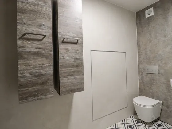 A wall hung WC with wooden cupboards above it