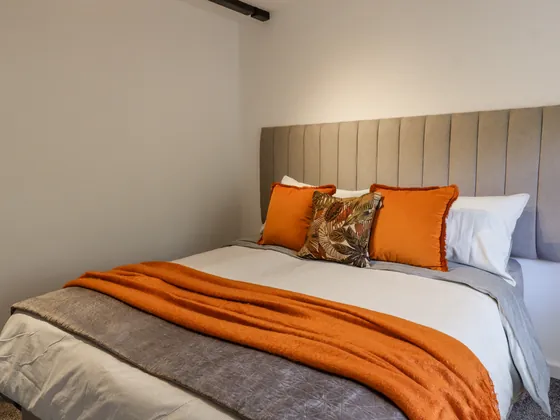 The double bed close up, made up with orange and patterned cushions