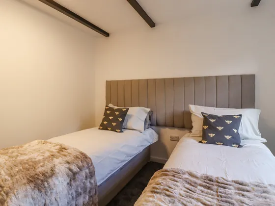 A twin room with beige headboards and fur throws across the beds