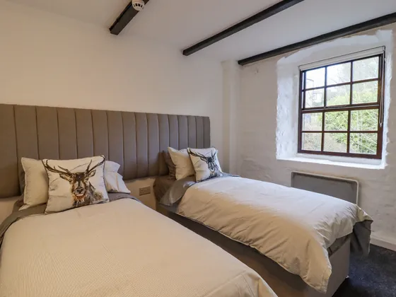 A twin room with stag cushions and trees showing through the window