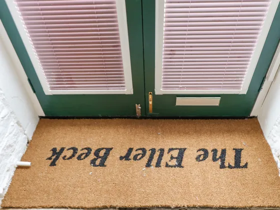 A coir doormat printed The Eller Beck lying inside the green front door