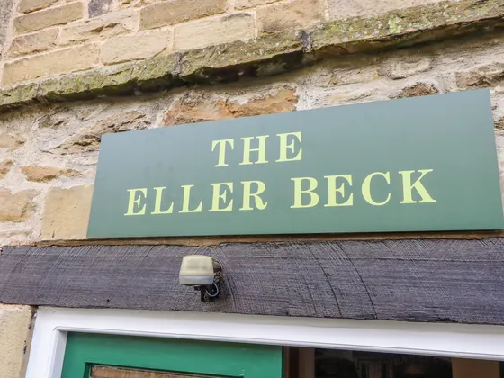 A green sign lettered The Eller Beck fixed to the stone wall above the door