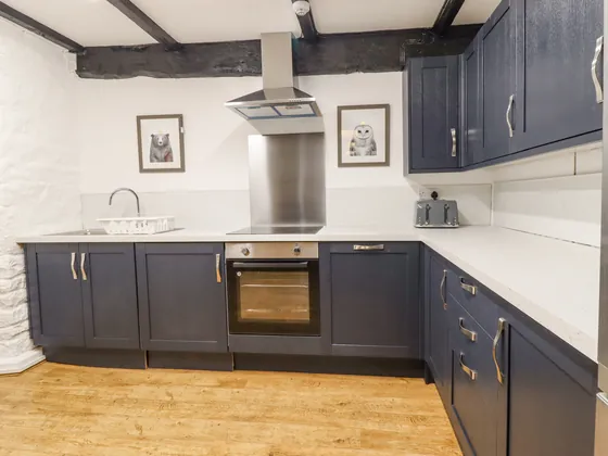 The kitchen corner with oven, hob, extractor hood and white worktops