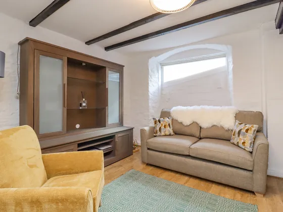 A sofa with a white throw, a yellow armchair and a wooden cabinet