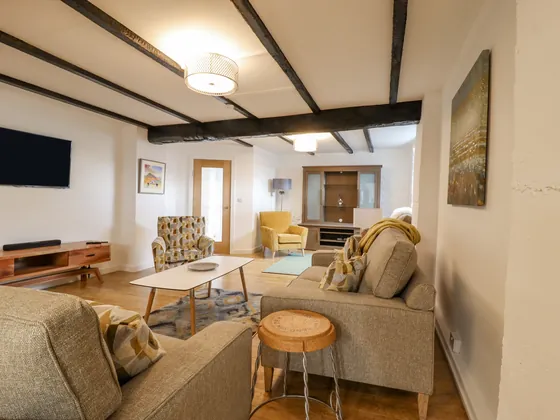 The open plan living space seen down its length, with dark ceiling beams
