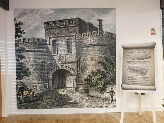 A welcome scroll on an easel in front of a wall sized engraving of Skipton Castle gatehouse