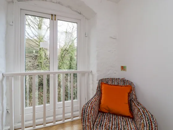 A patterned armchair beside a tall window with a white safety rail